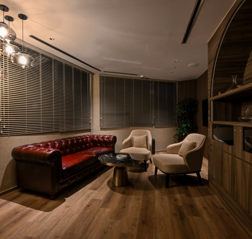 Small cosy room with deep red leather chair and 2 armchairs serving as the cigar room